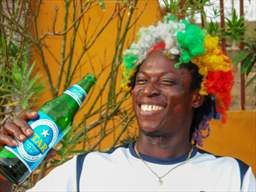 Man in colorful wig drinking Star beer in Ghana